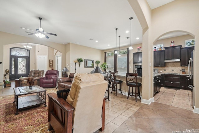 living area with arched walkways, baseboards, and light tile patterned floors