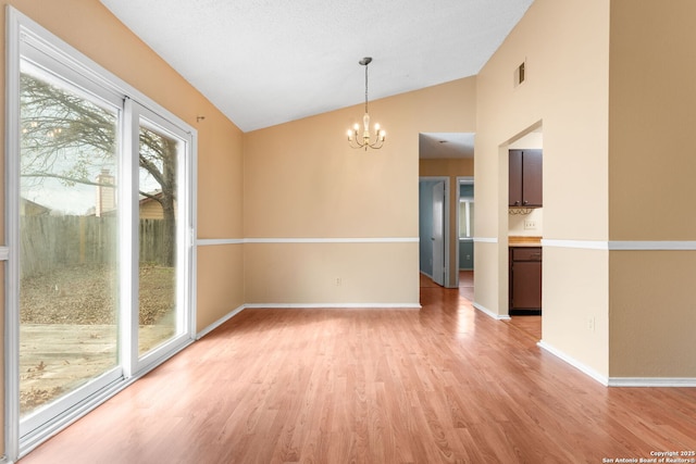 interior space with lofted ceiling, a chandelier, visible vents, baseboards, and light wood-type flooring