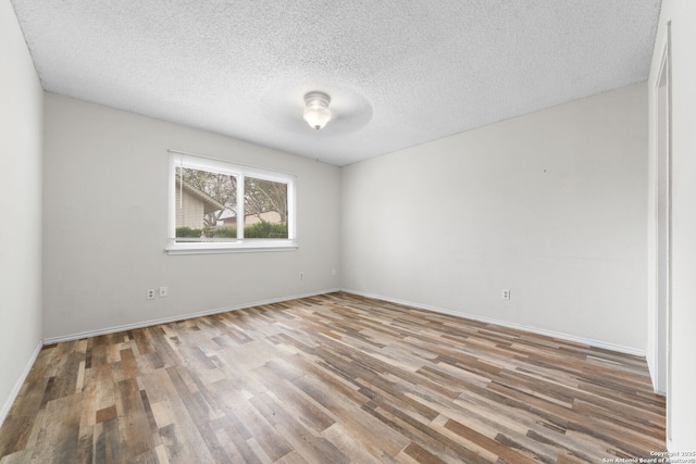 unfurnished room featuring a textured ceiling, wood finished floors, and baseboards