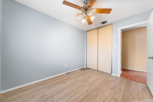 unfurnished bedroom with light wood-type flooring, baseboards, visible vents, and a closet