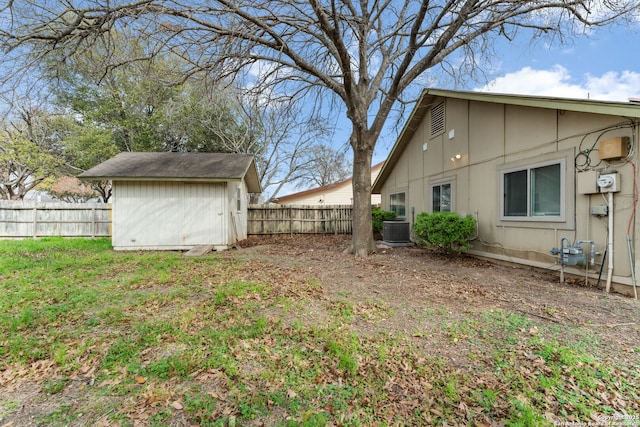 view of yard with a shed, an outdoor structure, a fenced backyard, and central air condition unit