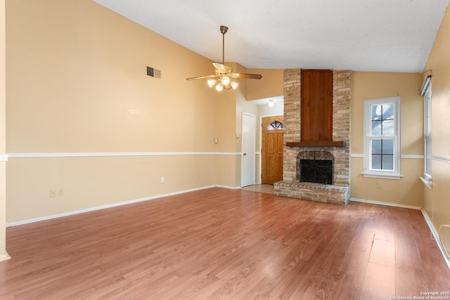 unfurnished living room with visible vents, a ceiling fan, baseboards, light wood-type flooring, and a brick fireplace