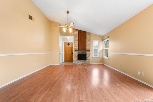 unfurnished living room with visible vents, a ceiling fan, lofted ceiling, light wood-style flooring, and a brick fireplace