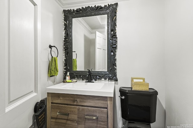 half bathroom featuring toilet, vanity, and crown molding