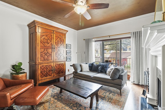 living room with a fireplace with flush hearth, ornamental molding, wood finished floors, and a ceiling fan