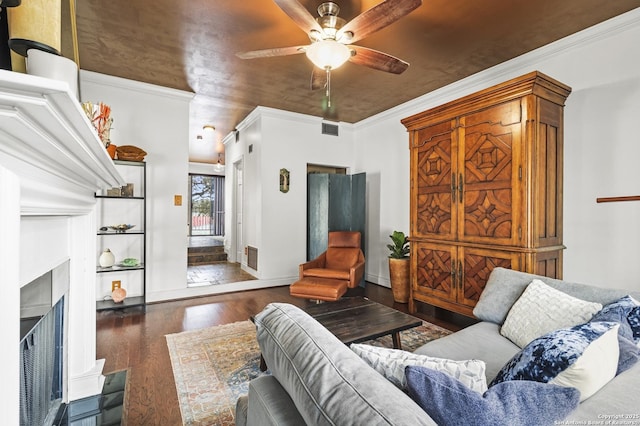 living area with ceiling fan, wood finished floors, visible vents, and crown molding