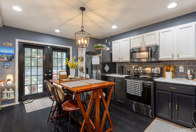 kitchen with stainless steel appliances, backsplash, light countertops, and white cabinetry