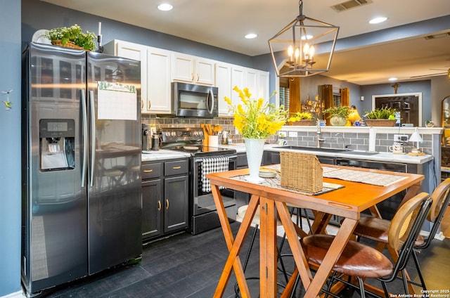 kitchen with a sink, visible vents, stainless steel appliances, and decorative backsplash