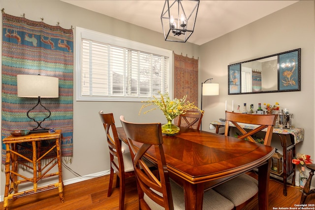 dining space with a notable chandelier, baseboards, and wood finished floors