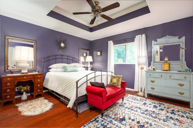 bedroom featuring ceiling fan, a tray ceiling, and wood finished floors