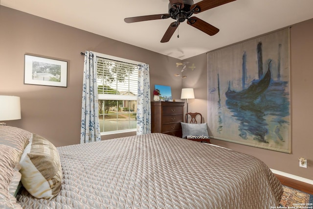 bedroom with ceiling fan, baseboards, and wood finished floors