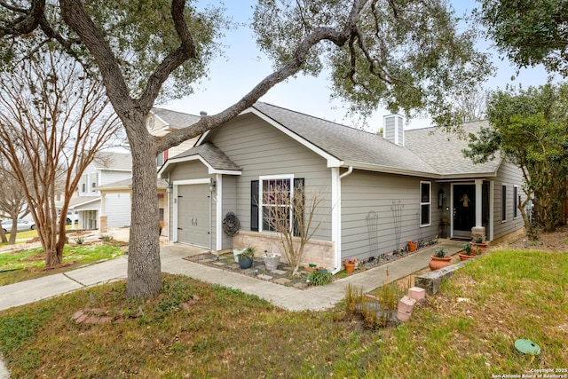 ranch-style house featuring a shingled roof, concrete driveway, a chimney, an attached garage, and brick siding