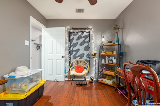 interior space featuring a ceiling fan, visible vents, and wood finished floors