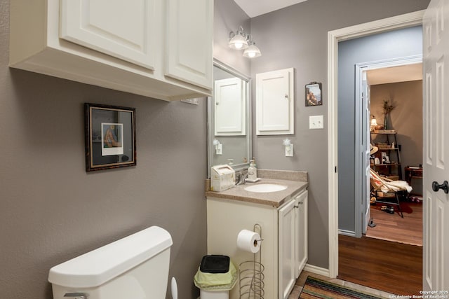 bathroom with toilet, baseboards, wood finished floors, and vanity