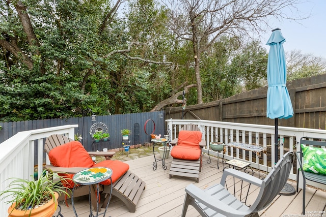 wooden terrace with a fenced backyard