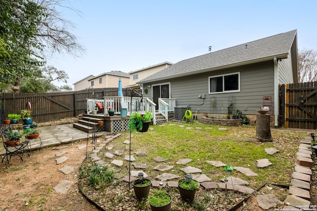 rear view of property with a lawn, a patio, a fenced backyard, roof with shingles, and a wooden deck