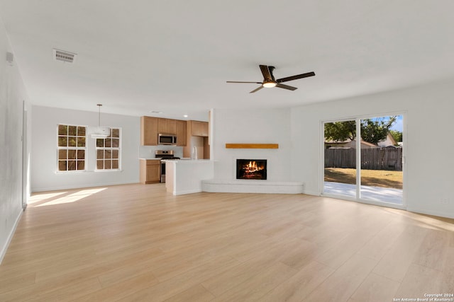 unfurnished living room with a fireplace, visible vents, a ceiling fan, baseboards, and light wood finished floors