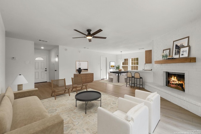 living room with baseboards, visible vents, a ceiling fan, light wood-type flooring, and a fireplace