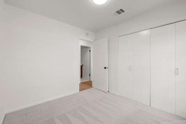 unfurnished bedroom with carpet, a closet, visible vents, and baseboards