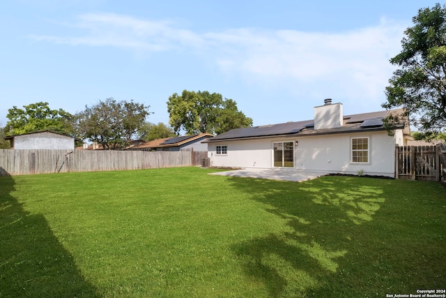 back of house with a fenced backyard, a patio, central AC, and a lawn