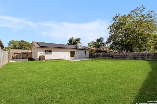 rear view of house with a patio, solar panels, a lawn, central AC, and a fenced backyard