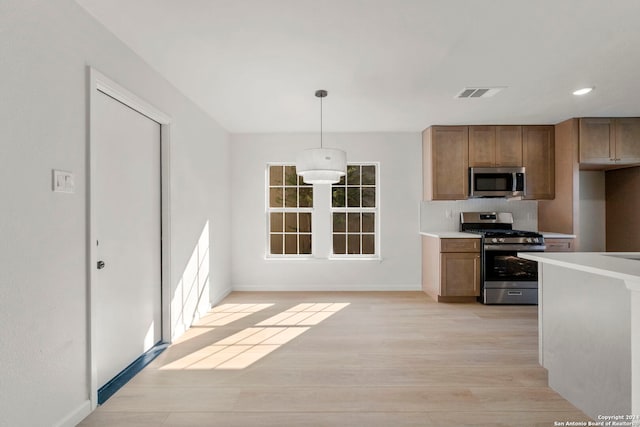 kitchen featuring stainless steel appliances, visible vents, light countertops, brown cabinetry, and light wood-type flooring