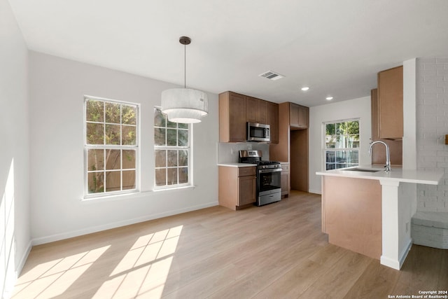 kitchen with stainless steel appliances, light countertops, visible vents, light wood-style floors, and a sink