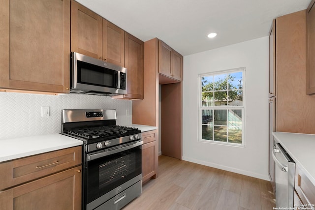 kitchen featuring stainless steel appliances, light countertops, light wood-style flooring, backsplash, and brown cabinetry