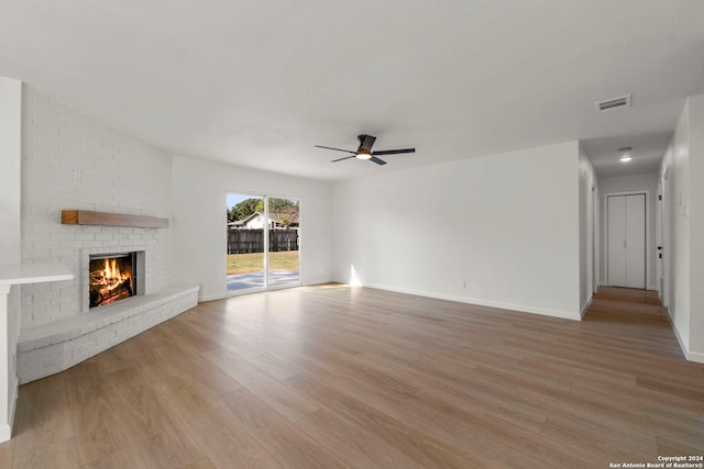 unfurnished living room featuring a brick fireplace, visible vents, light wood finished floors, and a ceiling fan