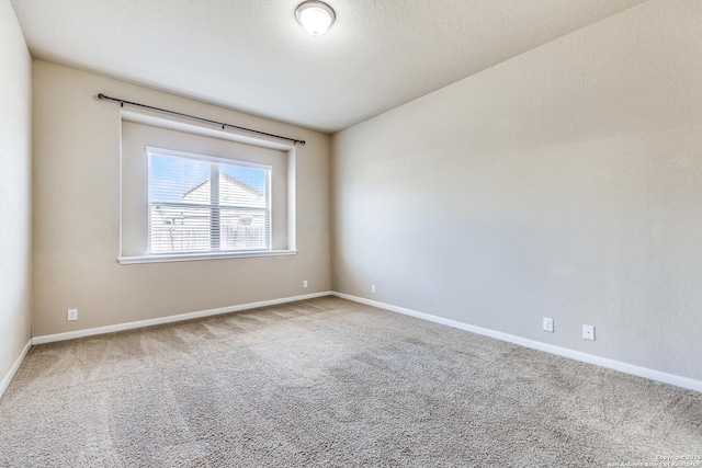 carpeted spare room with a textured ceiling and baseboards