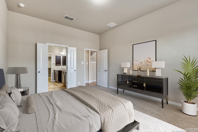 bedroom featuring visible vents, connected bathroom, light carpet, and baseboards