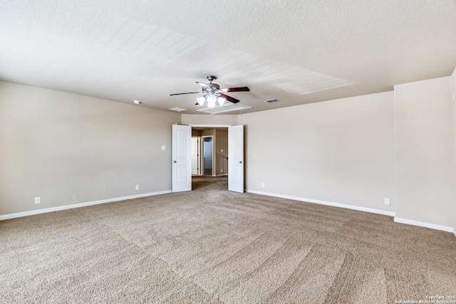 carpeted empty room featuring a textured ceiling, visible vents, and baseboards