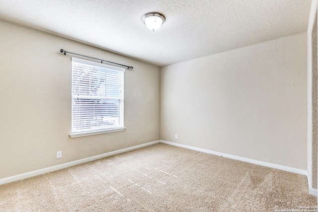 empty room with carpet, baseboards, and a textured ceiling