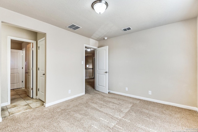 unfurnished bedroom featuring baseboards, visible vents, and light colored carpet