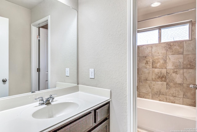 full bath with a textured wall, bathtub / shower combination, and vanity