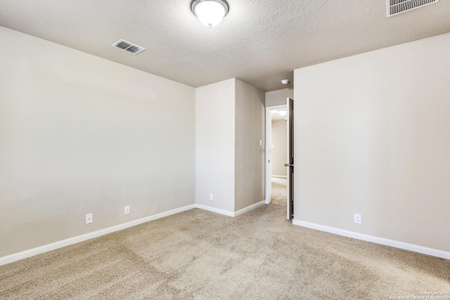 carpeted spare room with baseboards, visible vents, and a textured ceiling