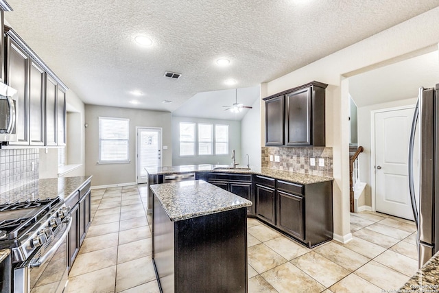 kitchen featuring ceiling fan, light stone counters, a sink, visible vents, and appliances with stainless steel finishes