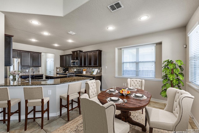 kitchen with stainless steel appliances, a sink, backsplash, and a breakfast bar area