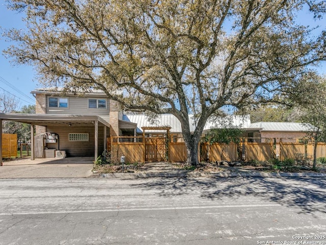 view of front of home featuring driveway, an attached carport, and a fenced front yard