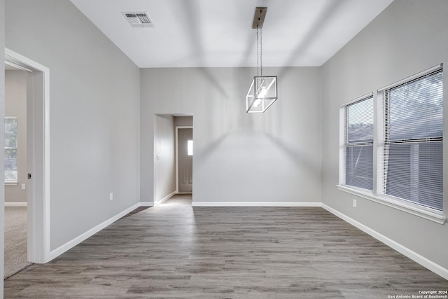 spare room featuring plenty of natural light, baseboards, visible vents, and wood finished floors