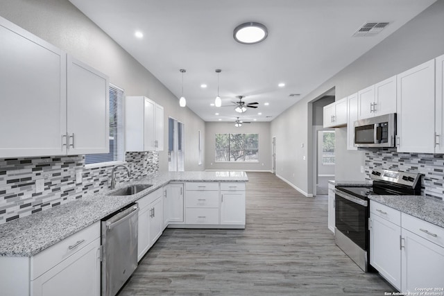 kitchen featuring stainless steel appliances, a peninsula, a sink, visible vents, and white cabinetry