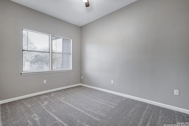 carpeted empty room featuring a ceiling fan and baseboards