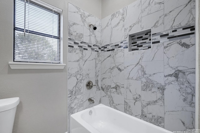 bathroom with a textured wall, shower / bathing tub combination, and toilet