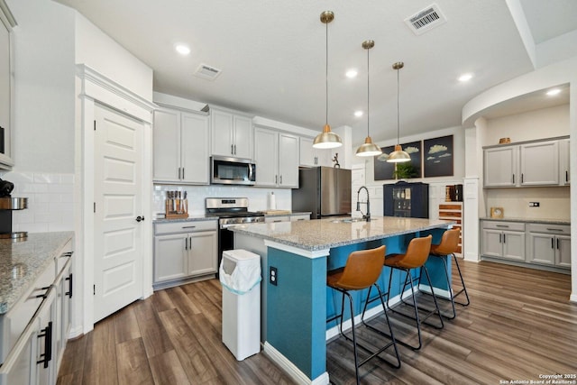 kitchen featuring appliances with stainless steel finishes, dark wood-type flooring, a sink, and visible vents