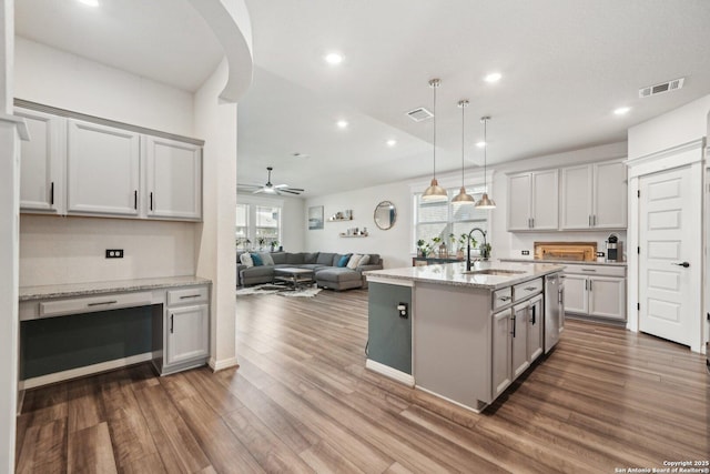 kitchen featuring visible vents, dark wood-type flooring, open floor plan, built in study area, and a sink