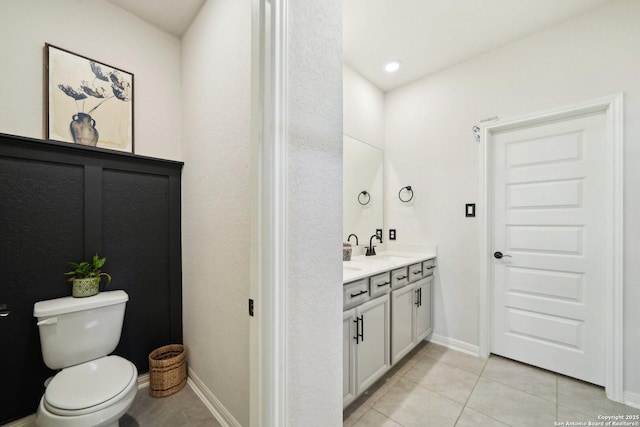 bathroom with tile patterned flooring, baseboards, toilet, and double vanity