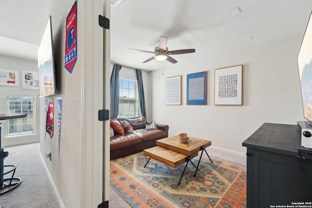 living area featuring a ceiling fan, baseboards, and carpet flooring