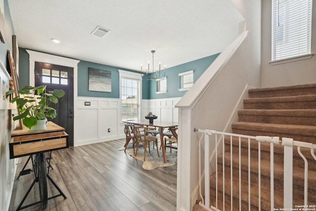 dining room featuring stairway, wainscoting, wood finished floors, and visible vents