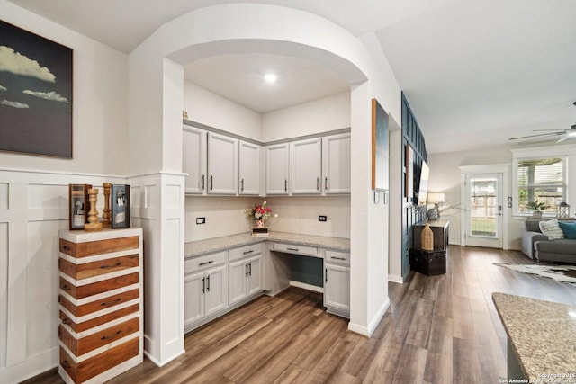 bar with a ceiling fan, arched walkways, and wood finished floors