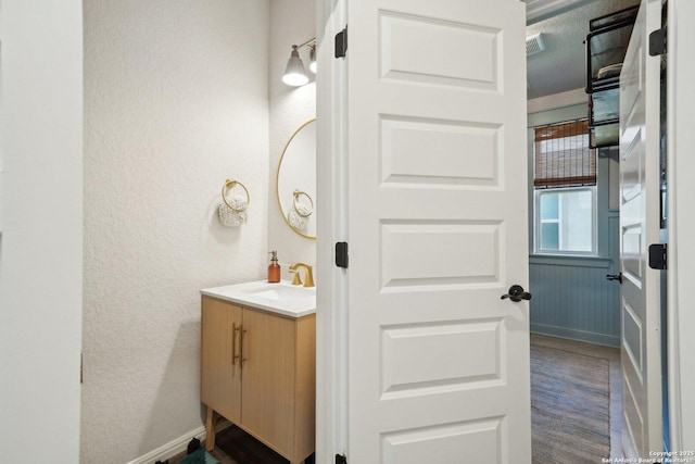 bathroom with visible vents, a textured wall, vanity, and baseboards